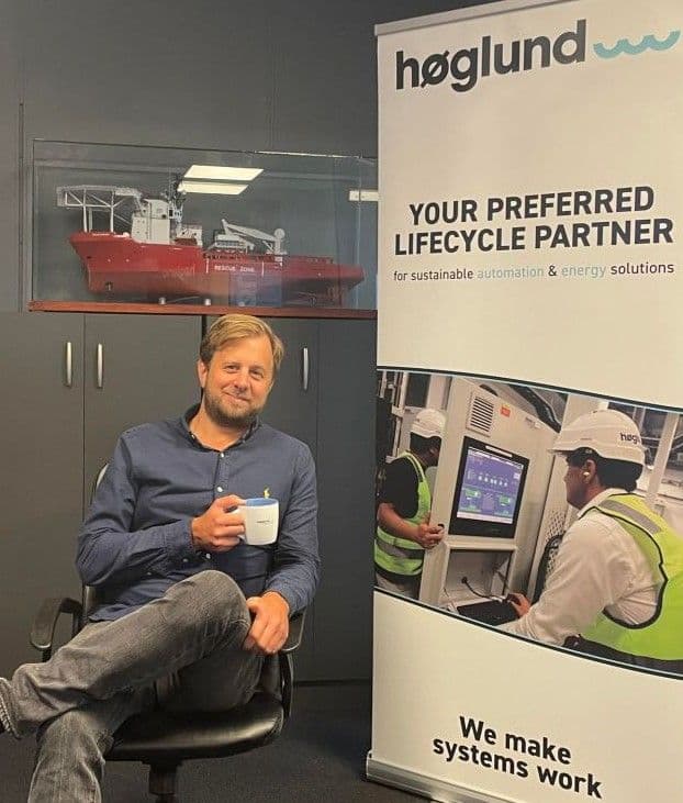 Anders Årdahl, CFO i Høglund AS, smilende mann med lyst hår og skjegg som holder en kaffekopp i hånden