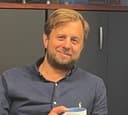 Anders Årdahl, CFO i Høglund AS, smilende mann med lyst hår og skjegg som holder en kaffekopp i hånden