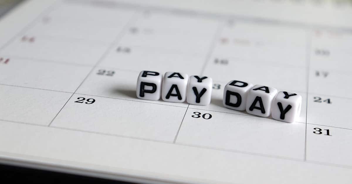 6 bokstavterninger som skriver ordet payday ligger oppå en kalender