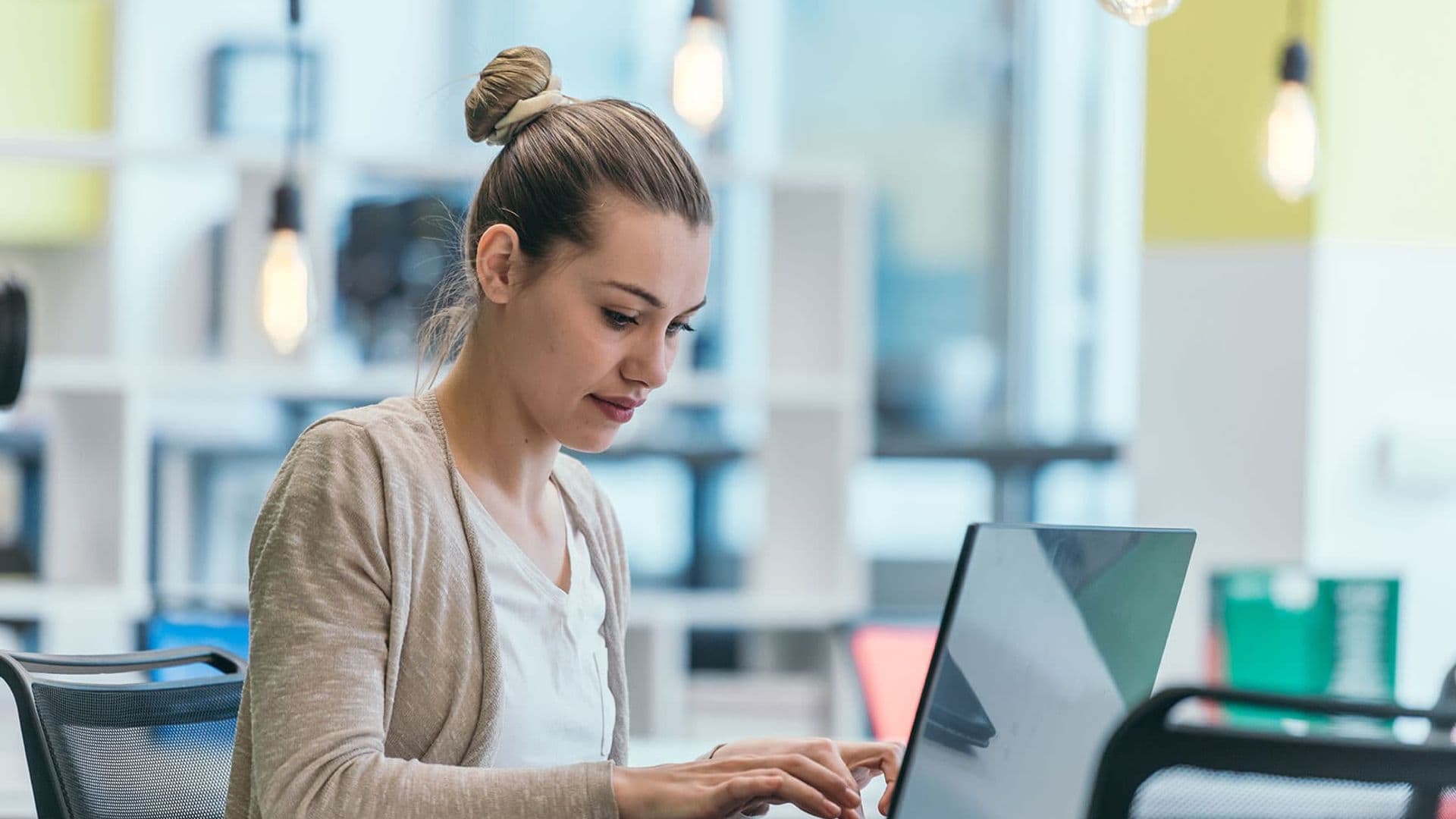 Bilde av en ung dame som sitter i et landskap og jobber på en laptop